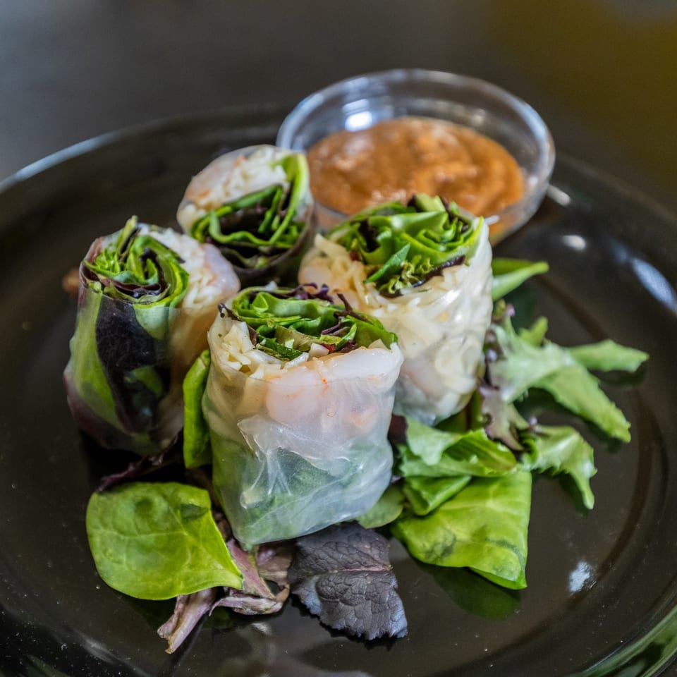 Four fresh Thai spring rolls with shrimp and greens, served with a peanut dipping sauce.